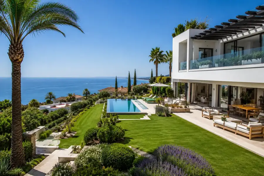 Villa de lujo con césped impecable, palmeras y piscina infinita frente al mar en la Costa del Sol
