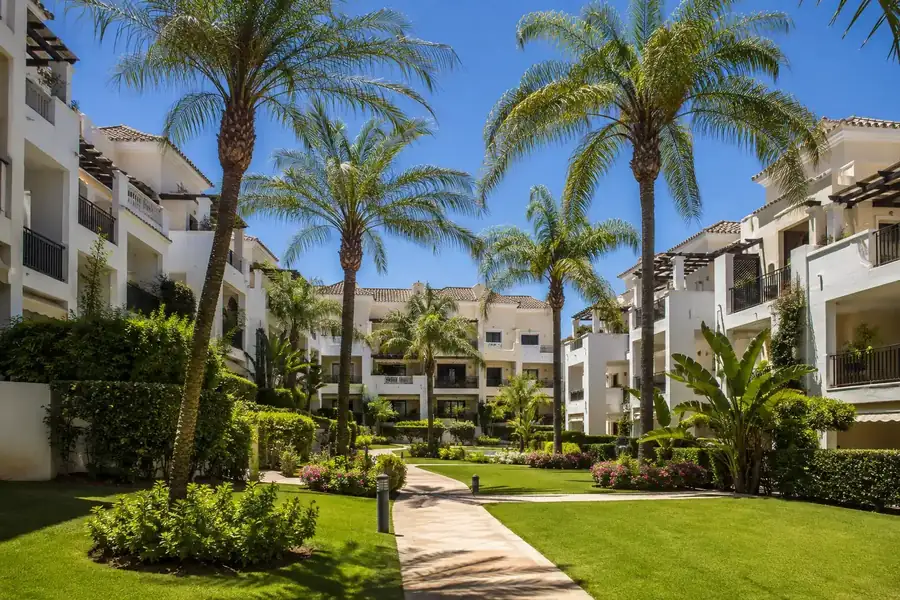 Zonas comunes con palmeras y piscina en una urbanización premium de Estepona
